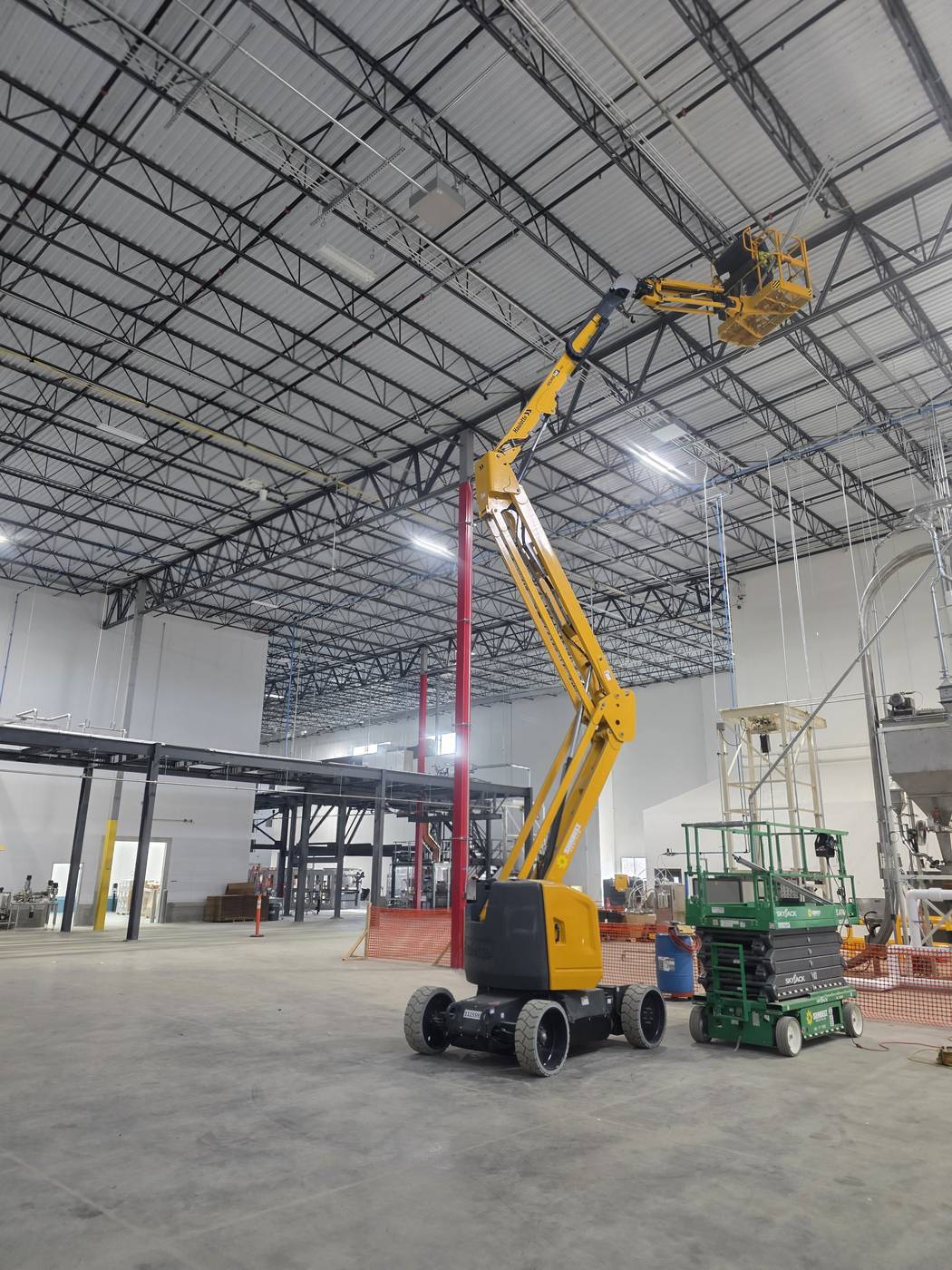Boom lift beside high racking inside a commercial warehouse during lighting work