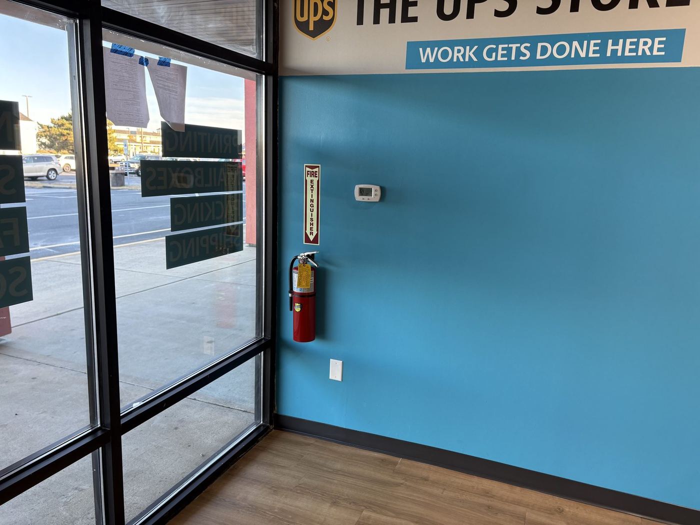 Electrical and data for a UPS Store upfit: finished storefront with a blue “Work gets done here” wall beside the storefront glass